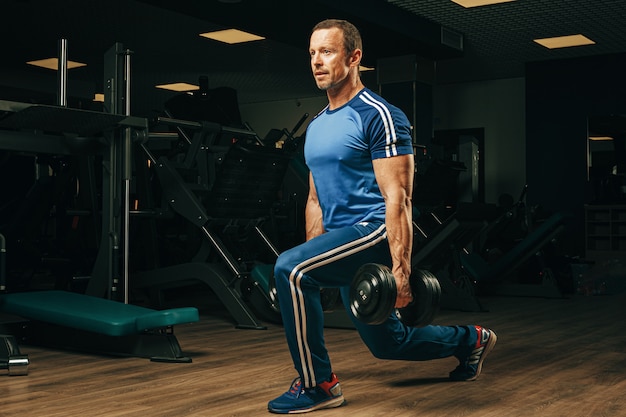 Senior man in his fifties lifting weights in a gym