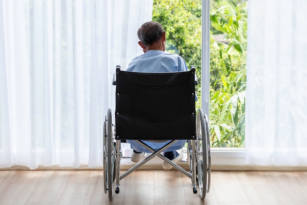 Старший мужчина в инвалидной коляске спиной в больнице.