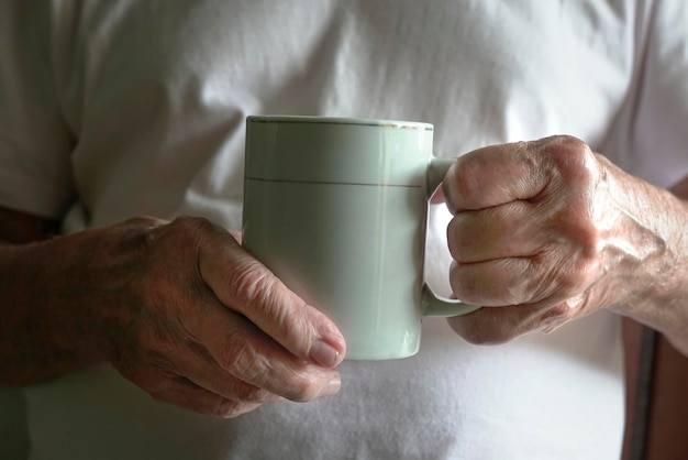 温かい飲み物のカップを保持している年配の男性