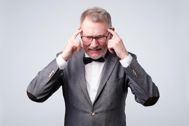 Senior man holds fingers on temples trying to remember