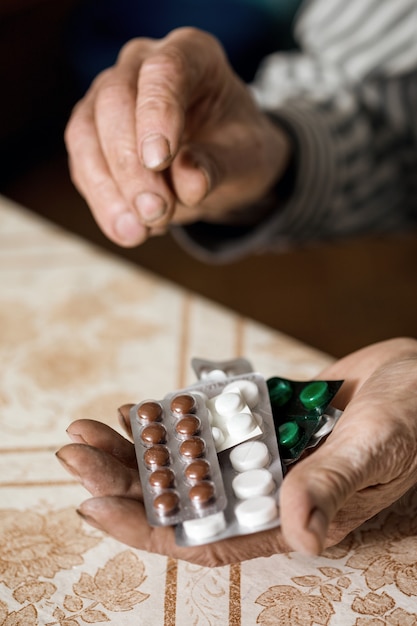 Photo senior man holds a pill in his hands