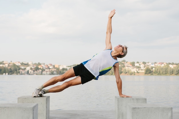 Senior man houdt zich bezig met sporten op de oever van het meer