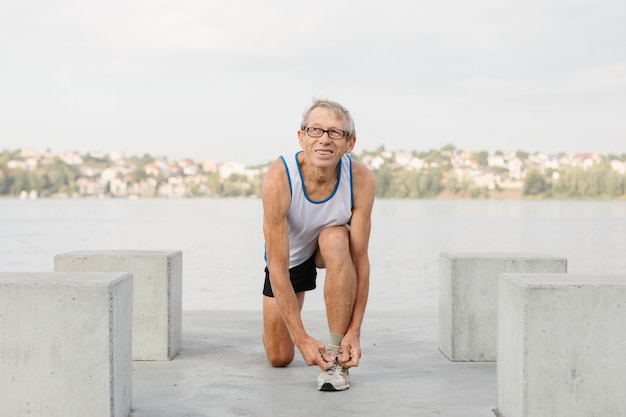 Senior man houdt zich bezig met sporten op de oever van het meer