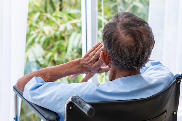 Senior man in zijn rolstoel met zijn rug in het ziekenhuis.