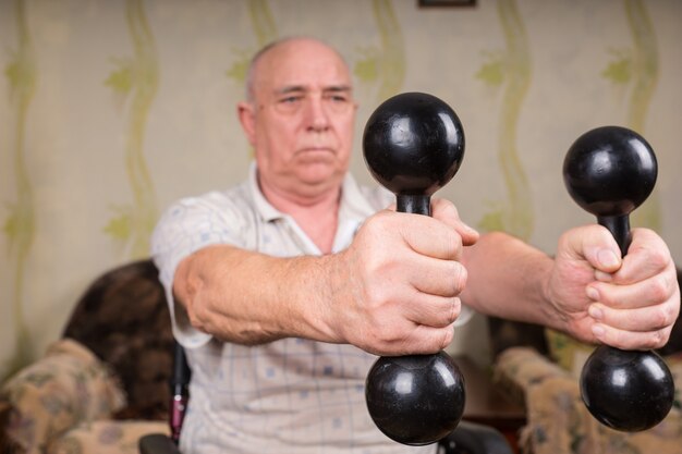 Senior man is focused on holding dumbbells