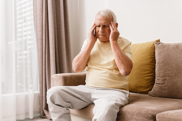 Photo senior man is suffering from headache at home