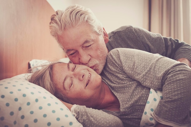Senior man kissing woman relaxing on bed at home
