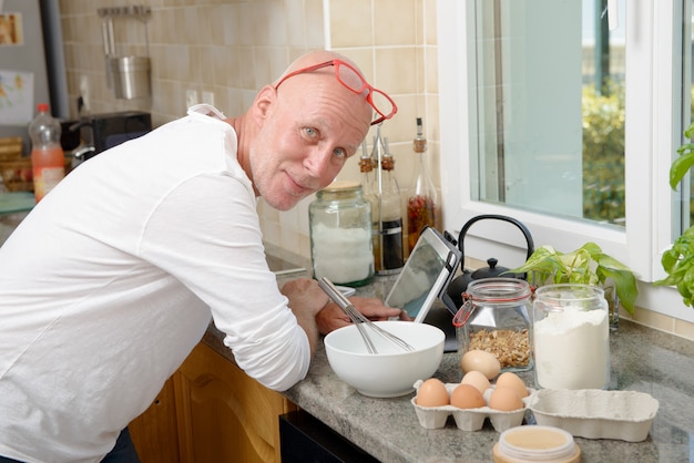 Uomo senior in cucina facendo uso della compressa