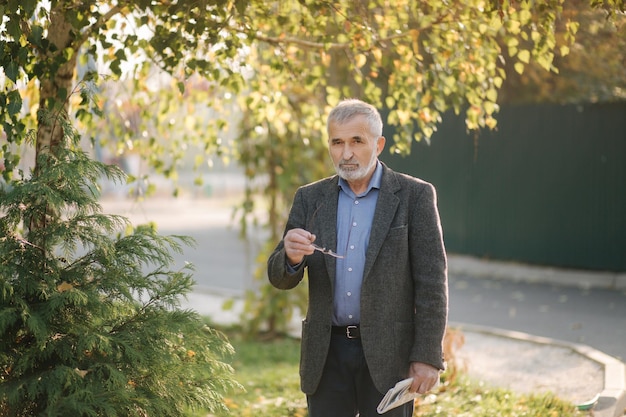 Senior man las een krant in het park Achtergrond van gele boom in de herfst