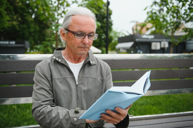 Senior man leest een boek in het park