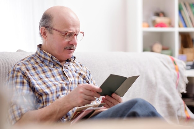 Senior man leest een boek op zijn bank