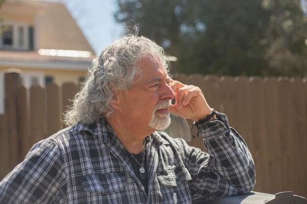 Photo senior man long gray hair against fence