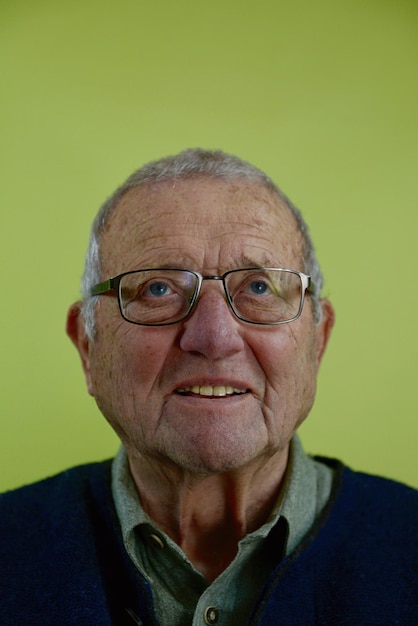 Фото Пожилой мужчина смотрит в сторону на зеленом фоне.