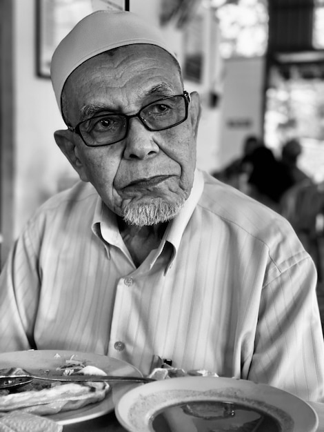 Foto uomo anziano che guarda lontano mentre è seduto in un ristorante