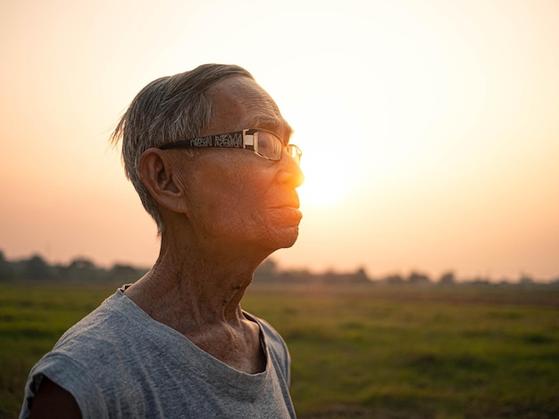 夕暮れの空に向かって立っている高齢の男性が目をそらしている