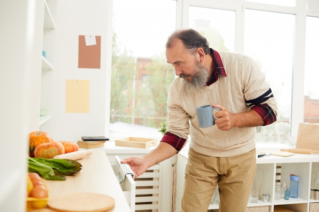 Uomo senior che cerca alimento in cucina