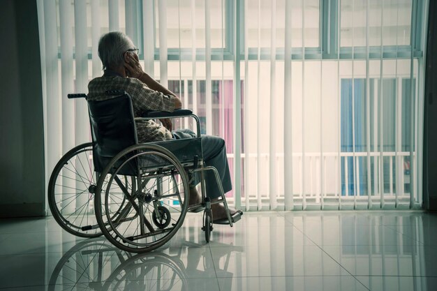 Senior man looking out the window in a wheelchair