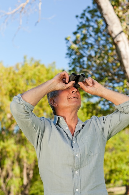 Senior man looking at the sky with his binoculars