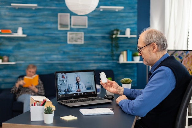 Senior man luisteren arts tijdens videoconferentie