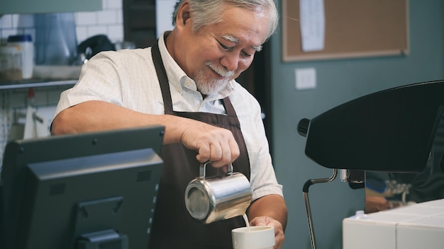 シニア男性はカウンターテーブルの後にコーヒーを作りますビジネスマンはコーヒーマシンを使用してコーヒーを作ります