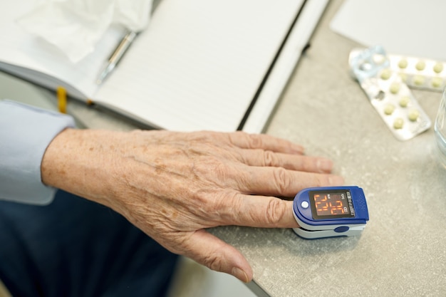 Photo senior man measuring his pulse and body oxygen with oximeter