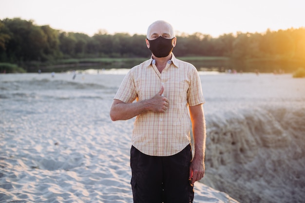 Senior man met beschermend masker duim opdagen, coronavirus, ziekte, infectie, quarantaine, medisch masker