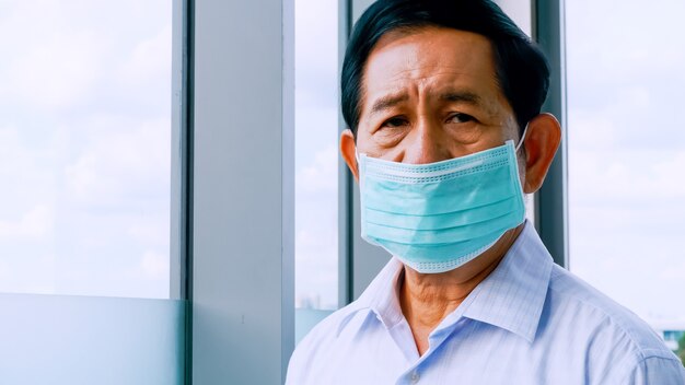 Senior man met beschermende gezichtsmaskers tijdens quarantaine thuis.