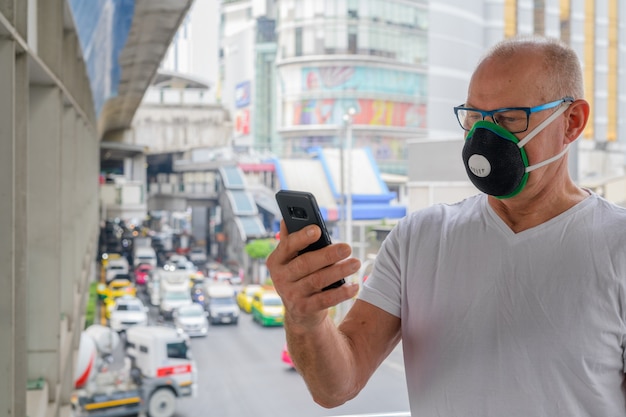 Senior man met gezichtsmasker om te beschermen tegen vervuiling smog in de stad