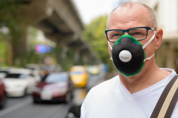 Senior man met gezichtsmasker om te beschermen tegen vervuiling smog