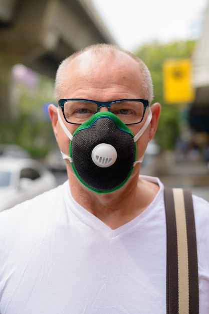 Senior man met gezichtsmasker om te beschermen tegen vervuiling smog