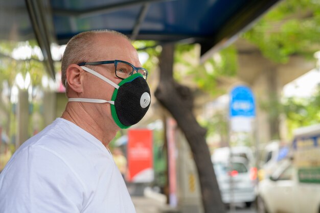 Senior man met gezichtsmasker om te beschermen tegen vervuiling smog