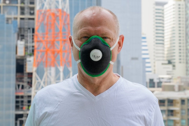 Senior man met gezichtsmasker om te beschermen tegen vervuiling smog