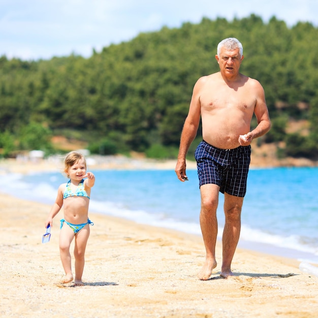Senior man met kleindochter wandelen op het prachtige tropische strand