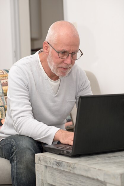 Senior man met laptop zitten in bank