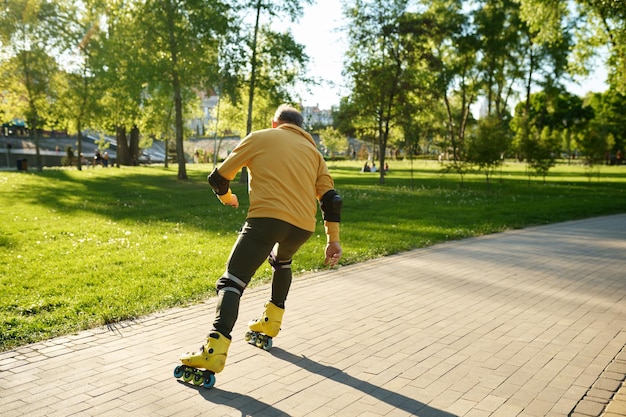 A senior man moving fast on roller skates outdoors