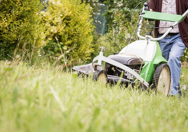 Senior man mowing the lawn with a lawnmower