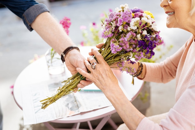 senior man offering flowers to wife