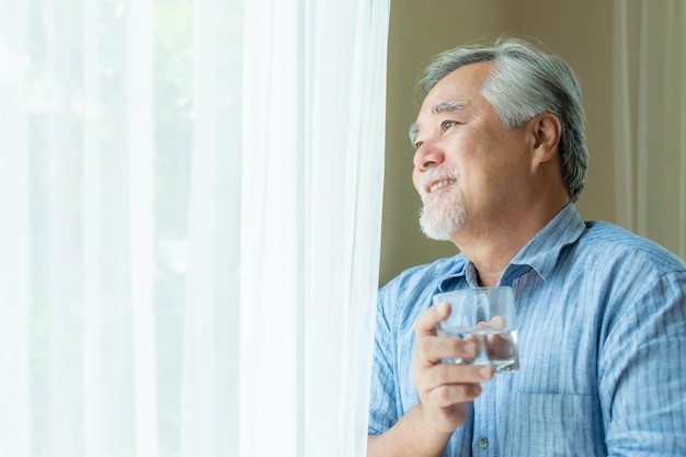 Senior man old man feel happy drinking fresh water in the morning enjoying time in his home indoor background lifestyle senior happiness concept