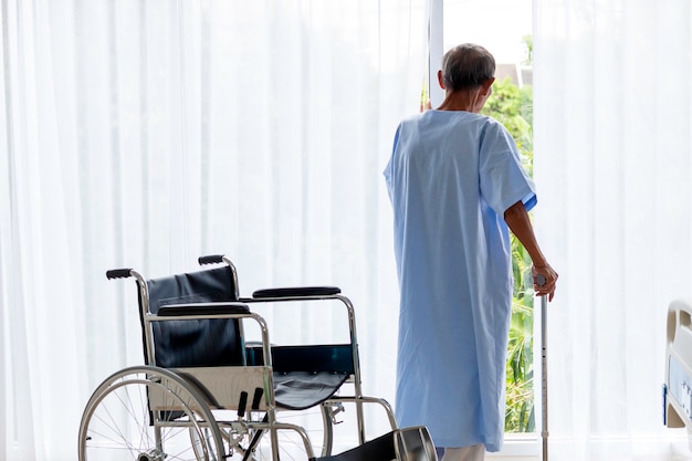 Senior man patient with walking stick in the hospital\
room.