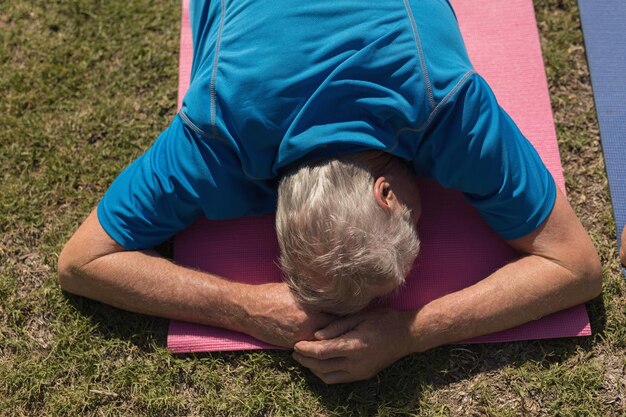 Photo senior man performing yoga in the park