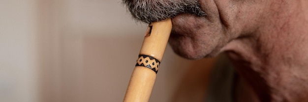 Senior man playing flute faceless unprofessional male elderly caucasian recorder people with a moustache with mouth and lips play on pipe amateur music close up at home hobbies and leisure banner