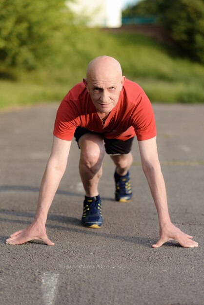 Senior man in position ready to run. Determined man ready for a sprint. Health lifestyle and Exercise Start Up Concept