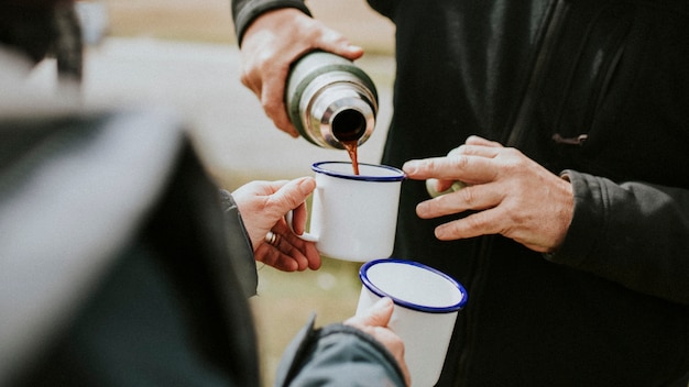 Senior man pouring morning coffee from a thermal bottle