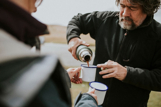 senior man pouring morning coffee from a thermal bottle