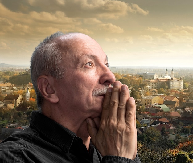 Senior man praying against cityscape