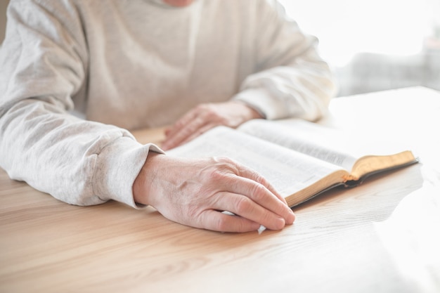 Senior man praying, reading  an old Bible in his hands.