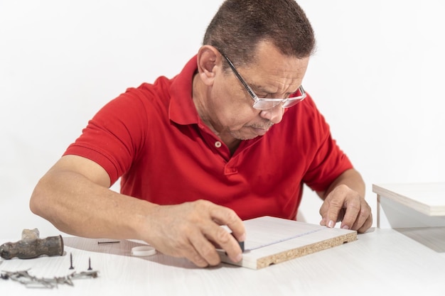 Photo senior man precisely marking furniture for assembly