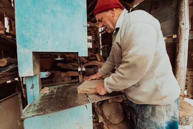 A senior man processing wood on a machine in an outdoor workshop
