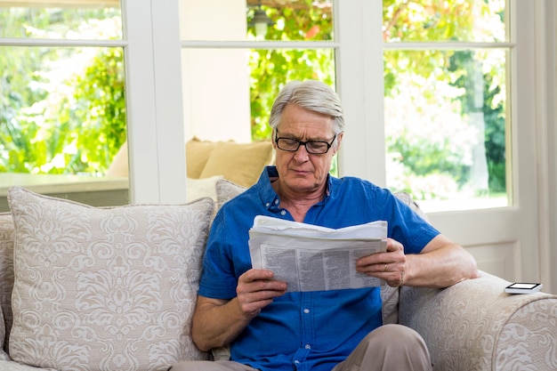 Senior man reading newspaper at home