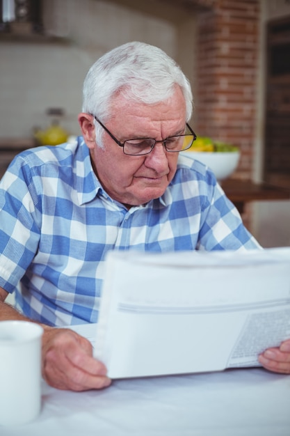 Senior man reading newspaper in kitchen